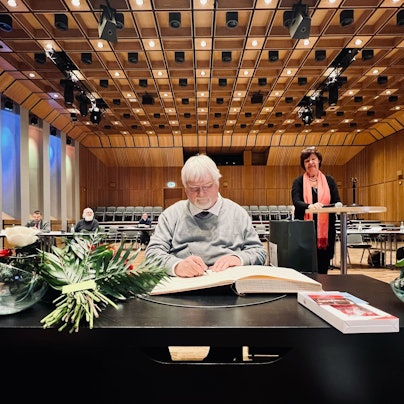 25 Jahre Mitglied der Bezirksvertretung: Dieter Redlin, Vorsitzender der Fraktion der Grünen in der Bezirksvertretung Porz, trägt sich in das Ehrenbuch des Stadtbezirks ein.