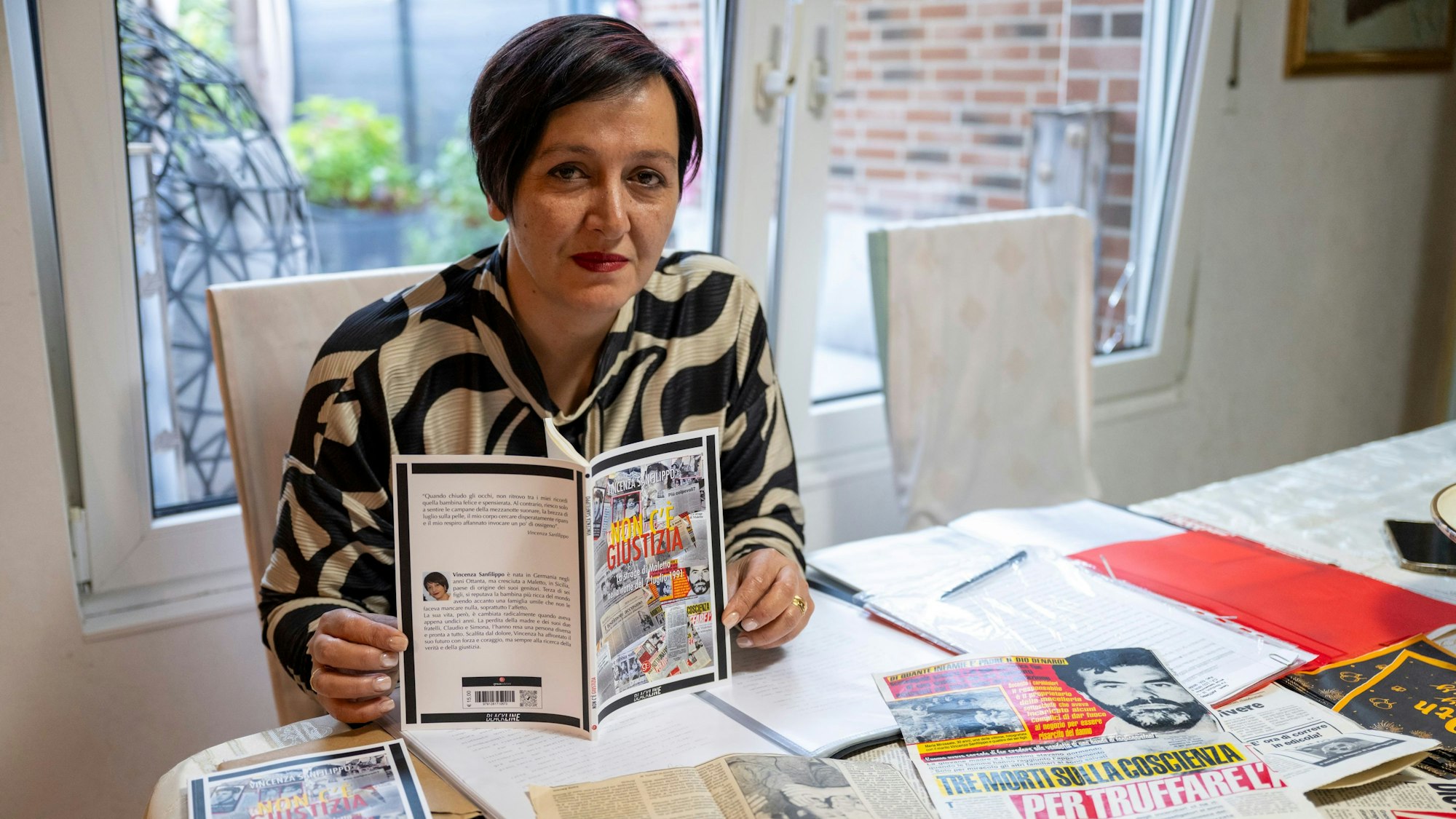 Vincenza Sanfilippo mit ihrem Buch und den vielen Zeitungsausschnitten, die sie gesammelt hat.