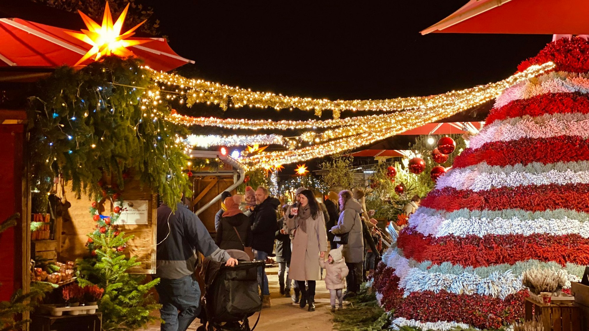 Das Foto zeigt Stände und eine mit roten und weißen Blüten geschmückte Winterpyramide auf dem Gertrudenhof.