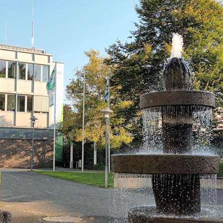 Vor einem Gebäude sprudelt ein Brunnen