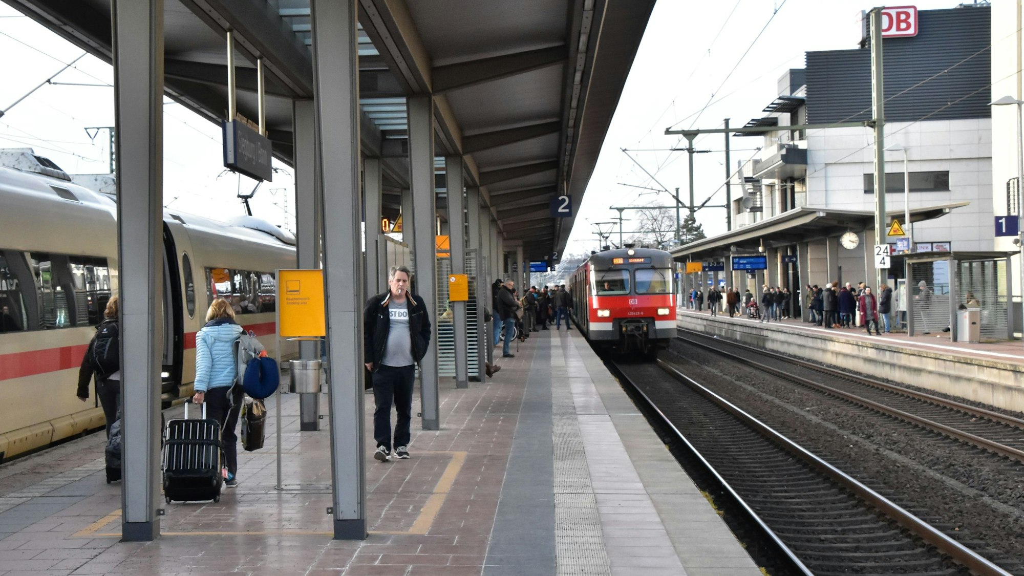 Ein Regionalzug fährt in den Siegburger Bahnhof auf Gleis 2 ein, einige Menschen stehen am Gleis.
