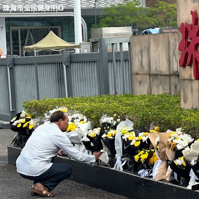 A man offers flowers outside the "Zhuhai People's Fitness Plaza" where a man rammed his car into people exercising at the sports center, in Zhuhai in southern China's Guangdong province on Wednesday, Nov. 13, 2024. (AP Photo/Ng Han Guan)