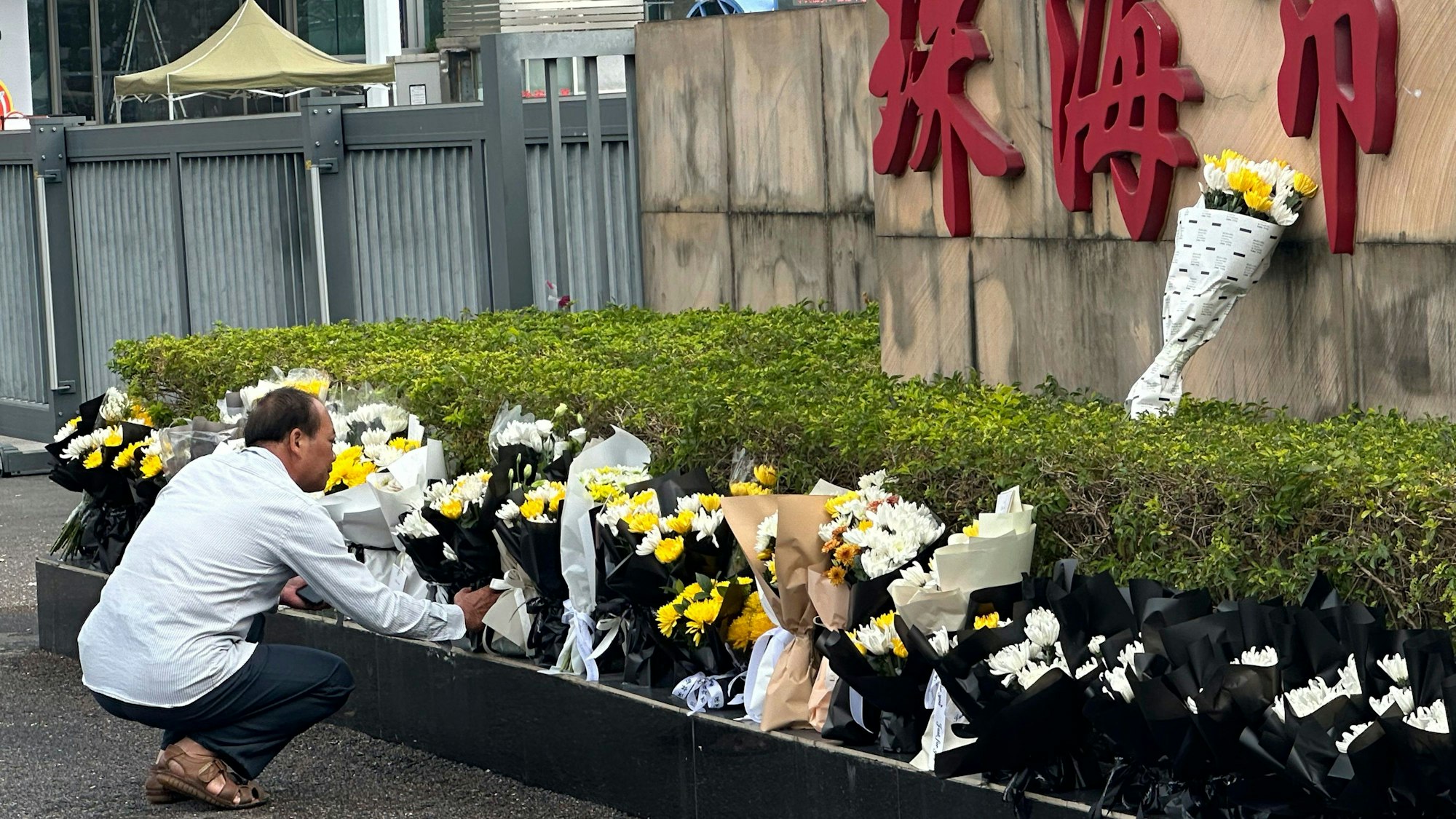 A man offers flowers outside the "Zhuhai People's Fitness Plaza" where a man rammed his car into people exercising at the sports center, in Zhuhai in southern China's Guangdong province on Wednesday, Nov. 13, 2024. (AP Photo/Ng Han Guan)