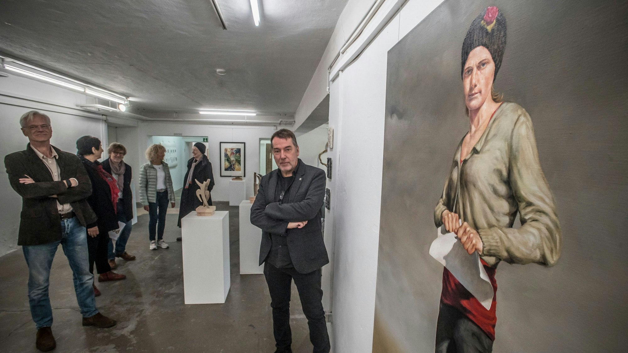 Die Jahresausstellung der AG Leverkusener Künstler im Bunker Opladen hat Papier zum Thema. In der Bildmitte: Dirk Schmitt, der das Bild rechts gemalt hat, auf dem eine Frau ein Blatt Papier zerreißt.