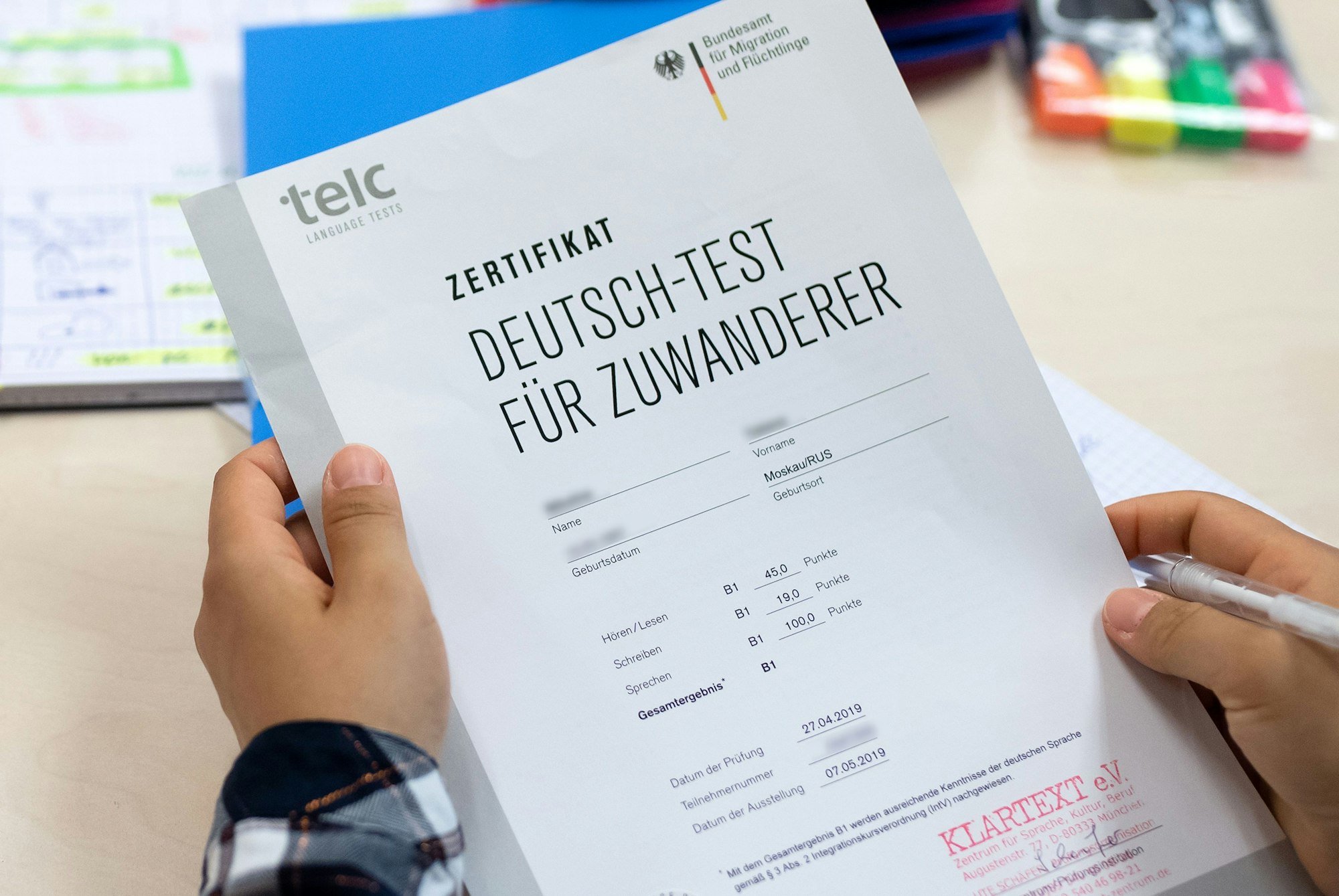 Eine Kursteilnehmerin zeigt das Zertifikat „Deutsch-Test für Zuwanderer“.