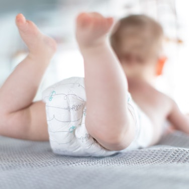 Ein Säugling trägt eine Windel, während er auf einer Kommode liegt.