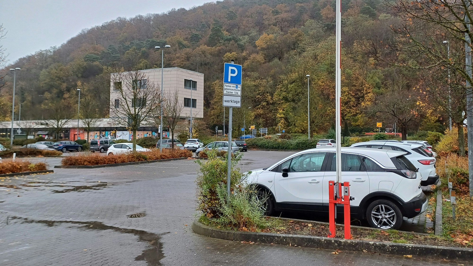 Das Foto zeigt den südlichen Teil des Aldi-Parkplatzes, auf dem Autos parken. Im Hintergrund ist ein Teil eines Gebäudes des City-Outlets zu erkennen.