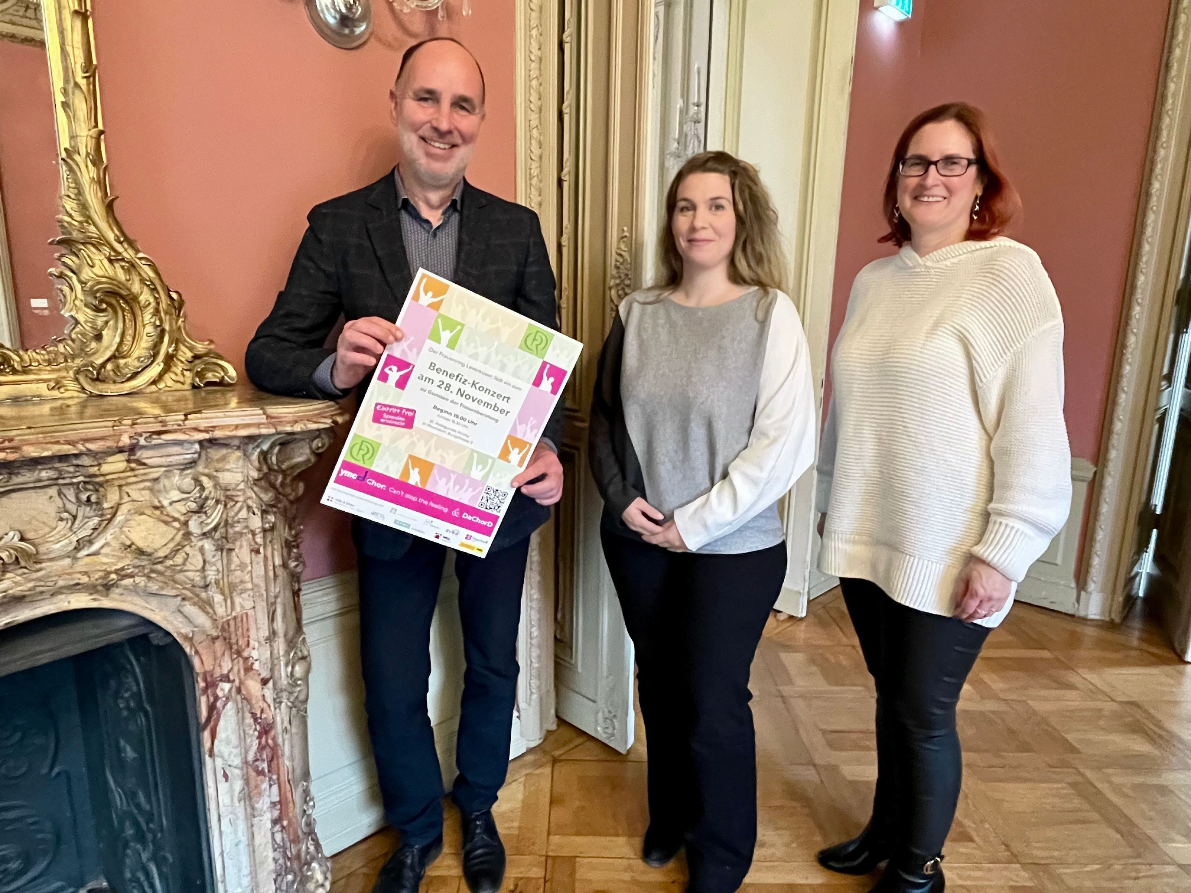 Drei Menschen mit Konzertplakat