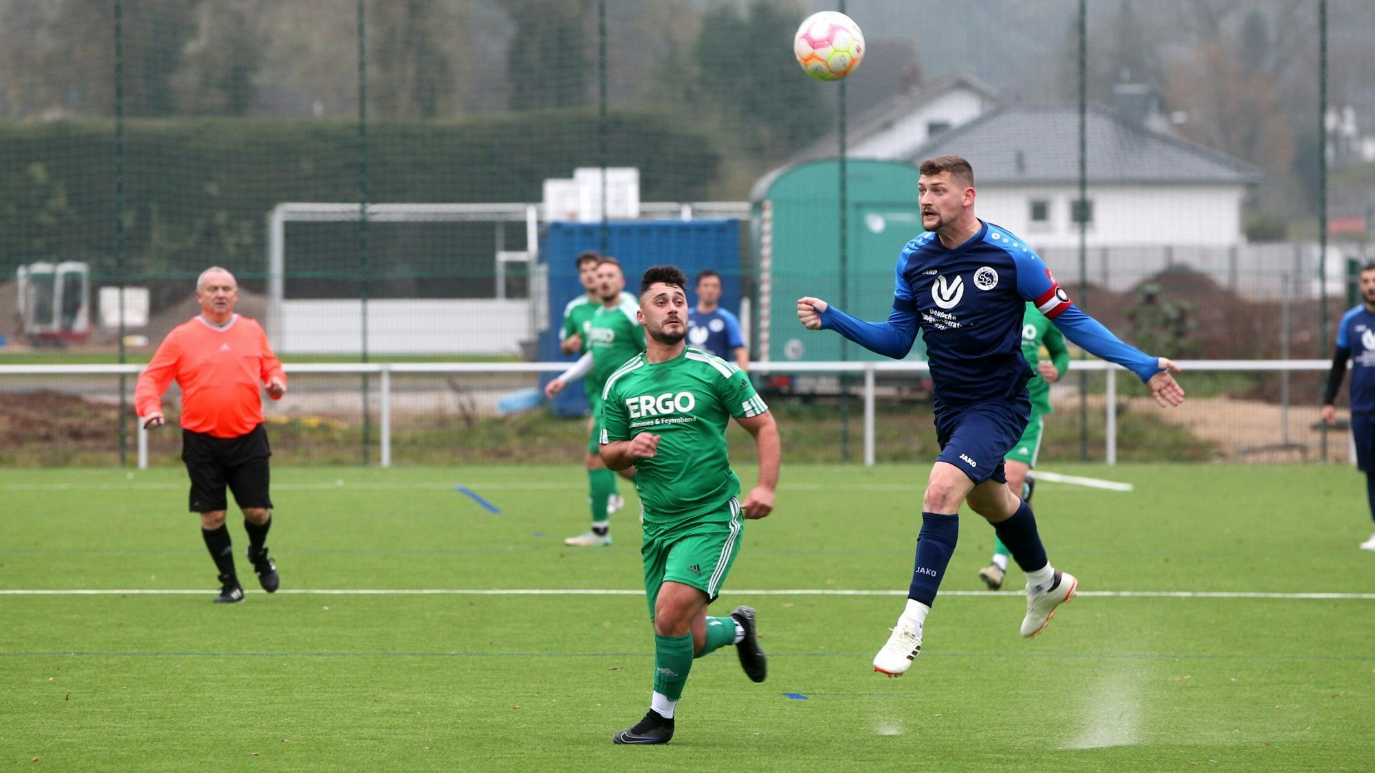 Der Kapitän des SC Roitzheim köpft einen Ball weg, sein Gegenspieler schaut zu. Das Granulat auf dem Kunstrasenplatz in Kall spritzt hoch.