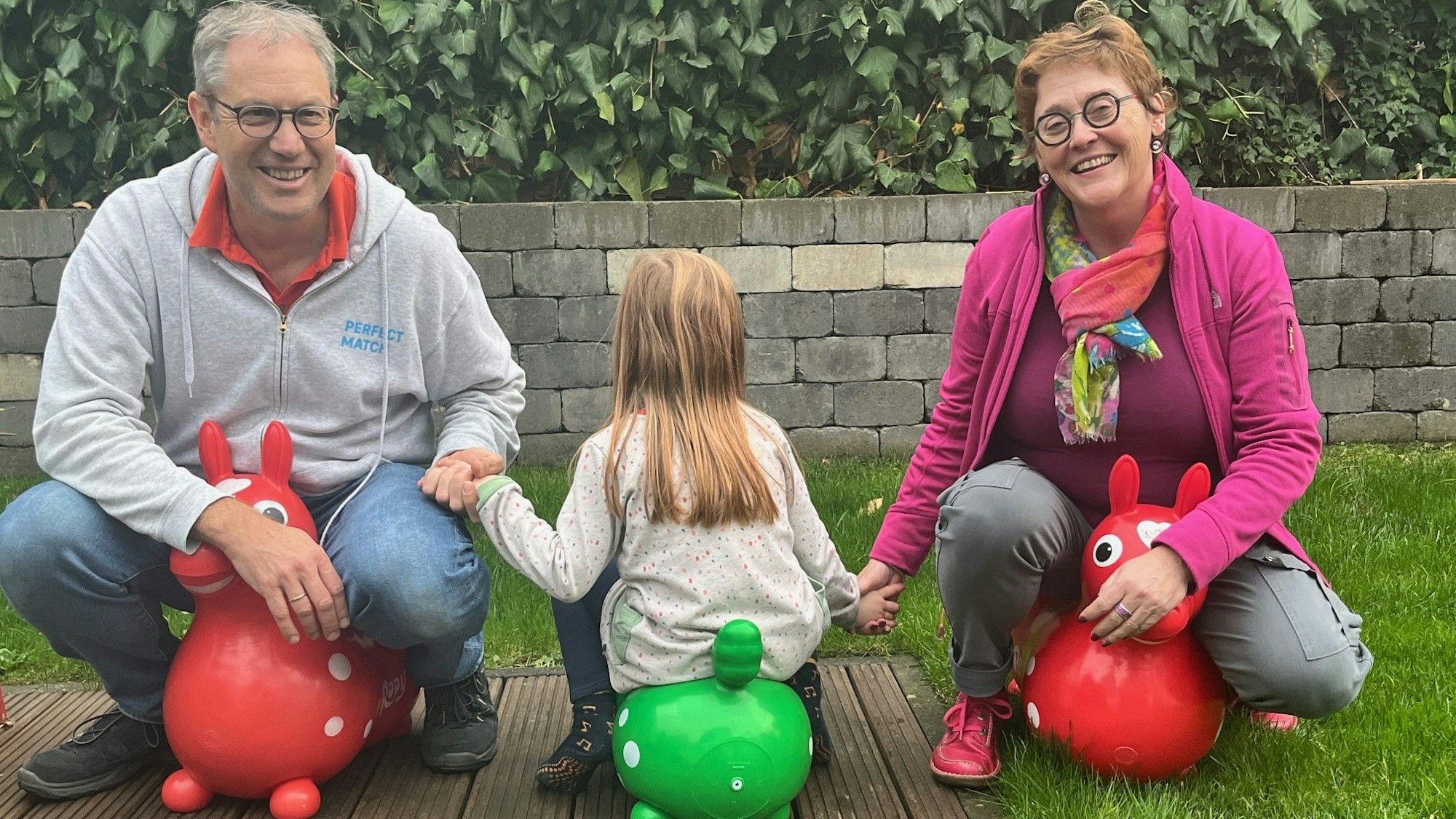 Achim S., 54, seine Tochter Anna und Familienpatin Heike Stumm vom SkF-Projekt „Laura und Laurenz“ sitzen auf bunten Gummi-Tieren.