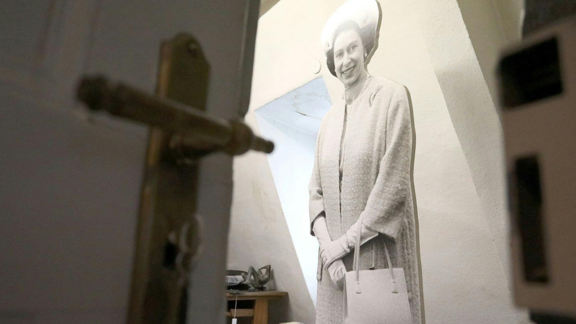 Blick an einer halb geöffneten Tür vorbei in einen Raum, in dem eine lebensgroße Figur von Queen Elizabeth steht.