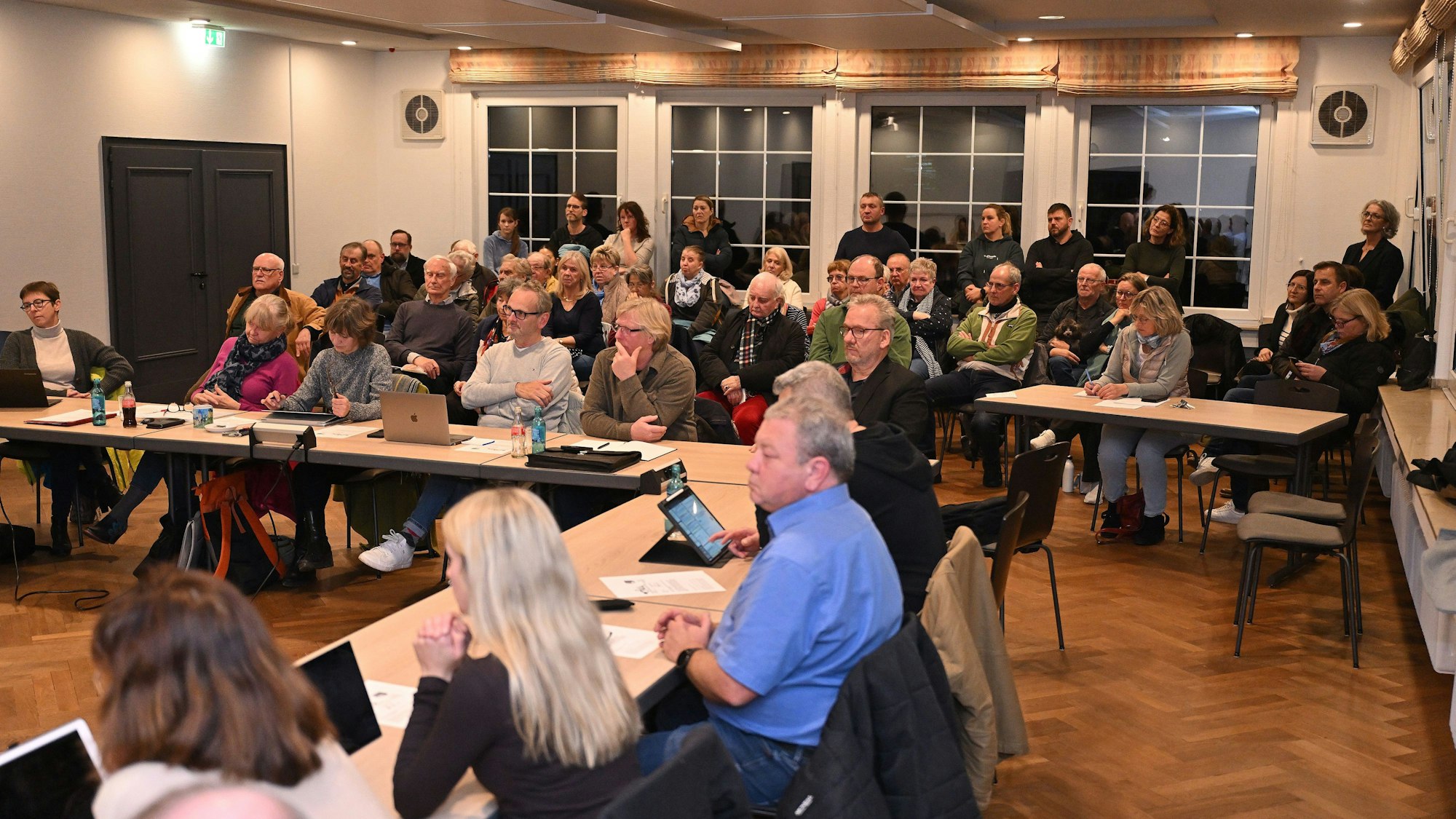Ein Ratssaal. An den Tischen sitzen Kommunalpolitiker, auf den Zuschauerplätzen dahinter sitzen viele Männer und Frauen.