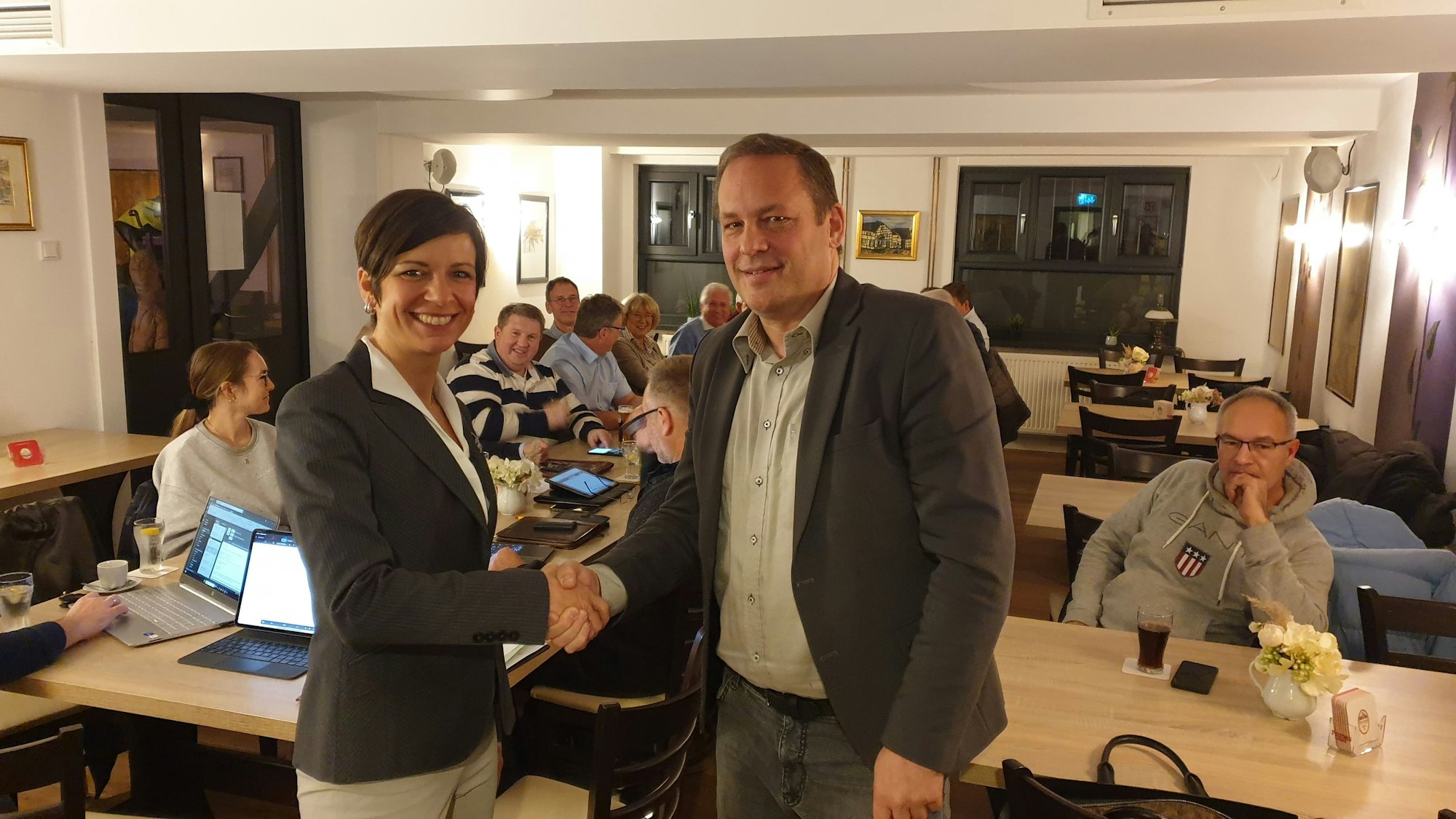 Der Parteivorsitzende schüttelt der Bürgermeisterin vor den Parteivorstandsmitgliedern die Hand.