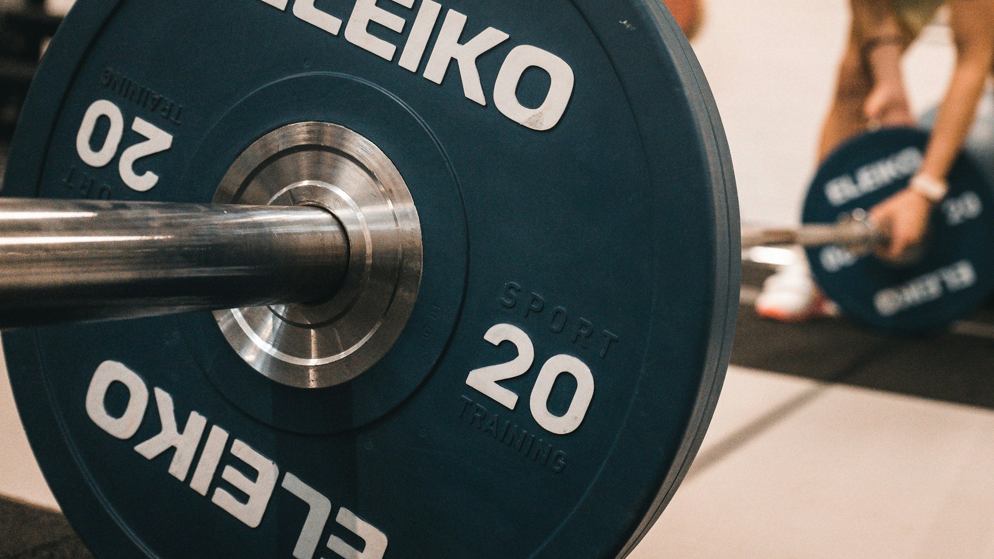 Eine Langhantelstange wird von einer Person mit Gewichten beladen.