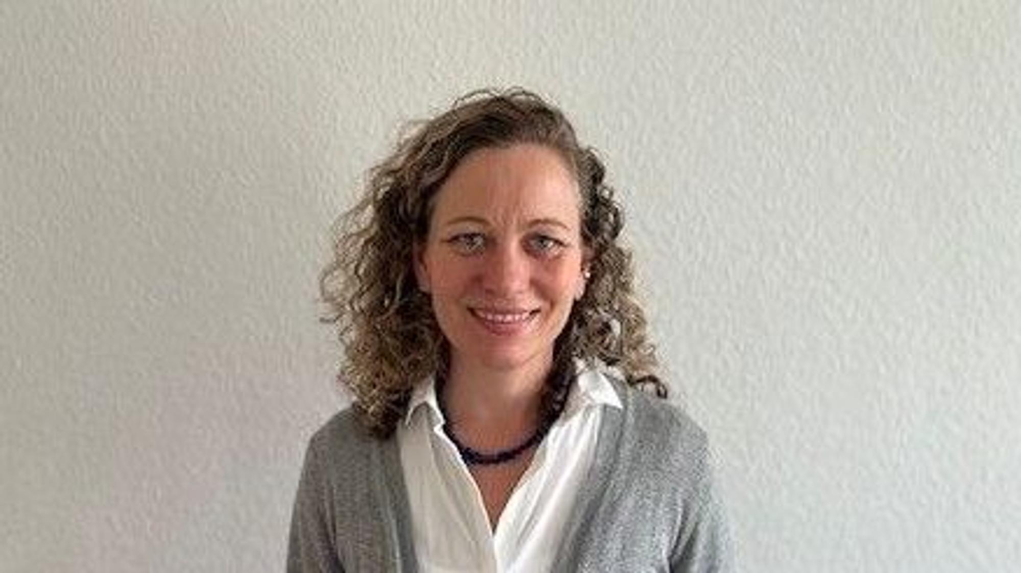 Susanne Heintz ist Koordinatorin des SkF-Familienpaten-Projekts „Laura und Laurenz“, sieht hat lange blonde, lockig Haare, trägt eine weiße Bluse und einen grauen Cardigan.