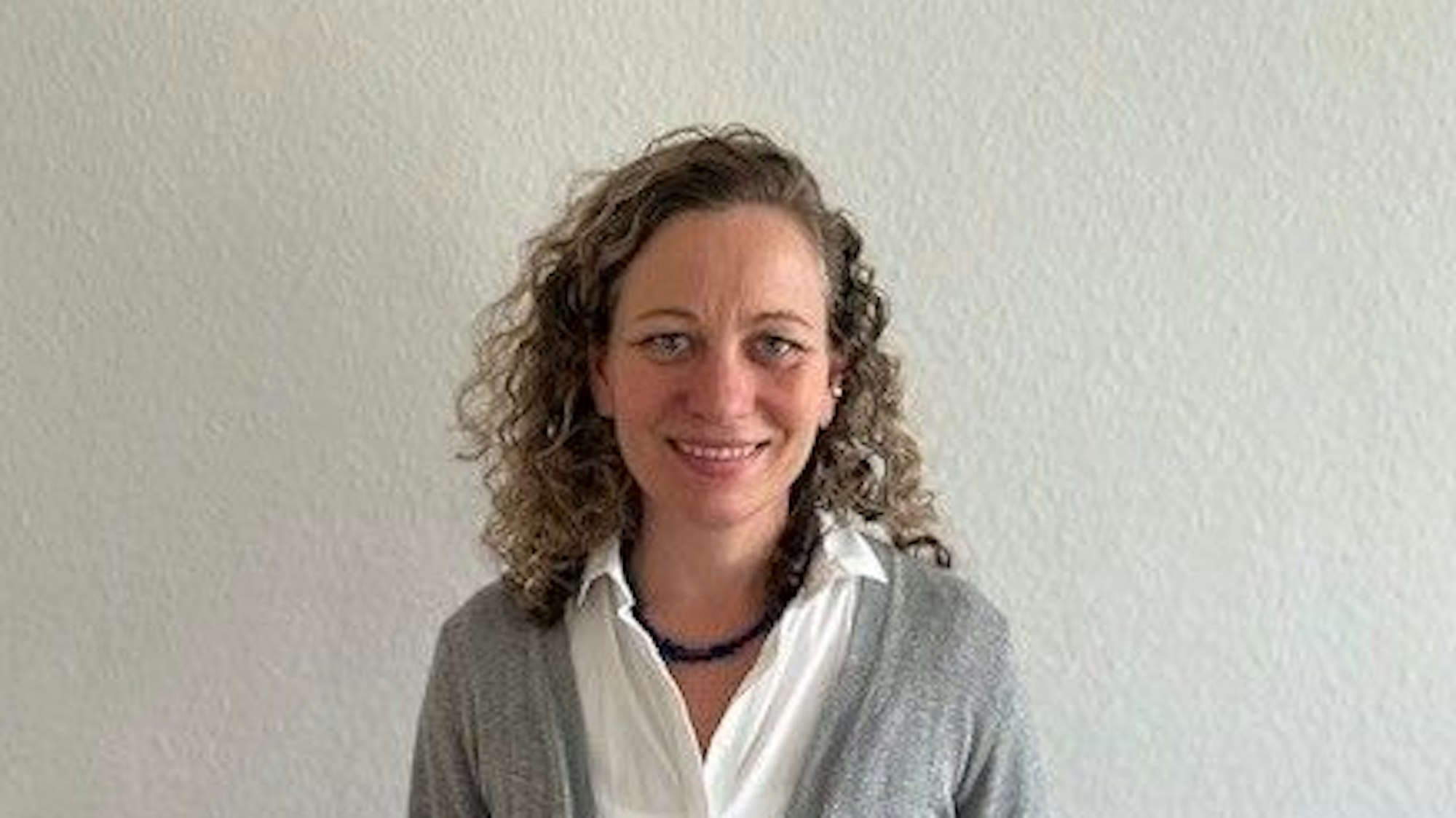 Susanne Heintz ist Koordinatorin des SkF-Familienpaten-Projekts „Laura und Laurenz“, sieht hat lange blonde, lockig Haare, trägt eine weiße Bluse und einen grauen Cardigan.