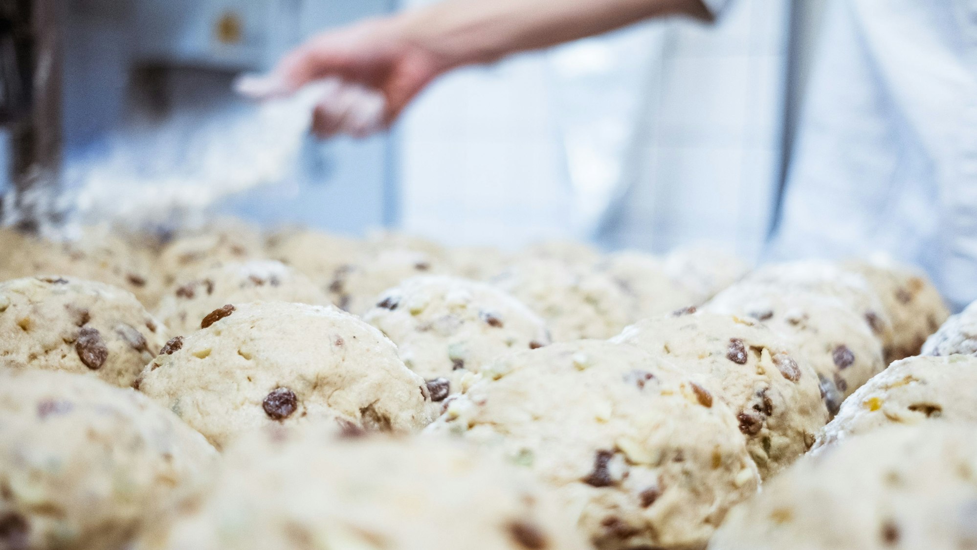 Produktion des begehrten Excelsior-Stollen in der hauseigenen Patisserie. Ein Patissier bestäubt die Teigwaren mit Mehl.