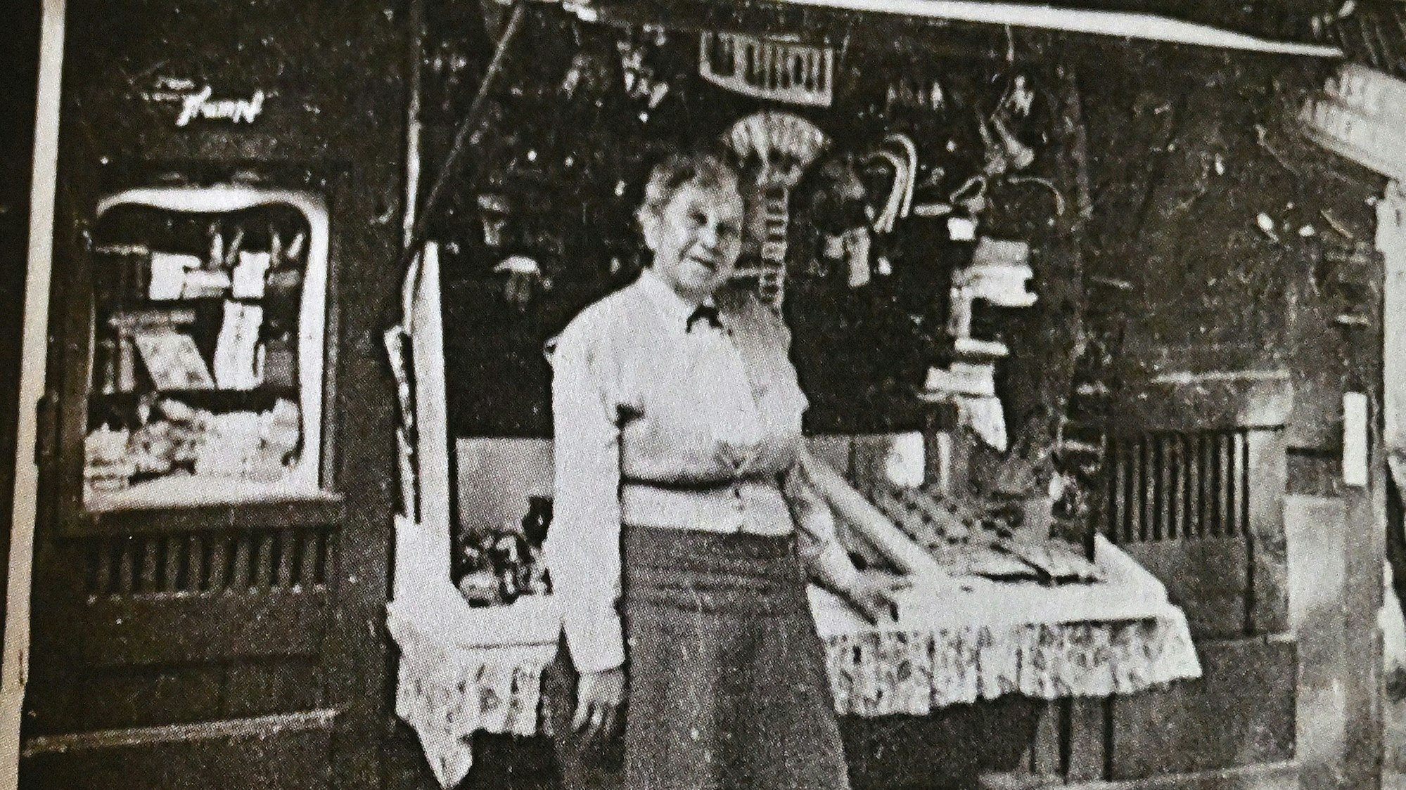 Eine ältere Frau steht vor einem historischen Andenkenbüdchen.