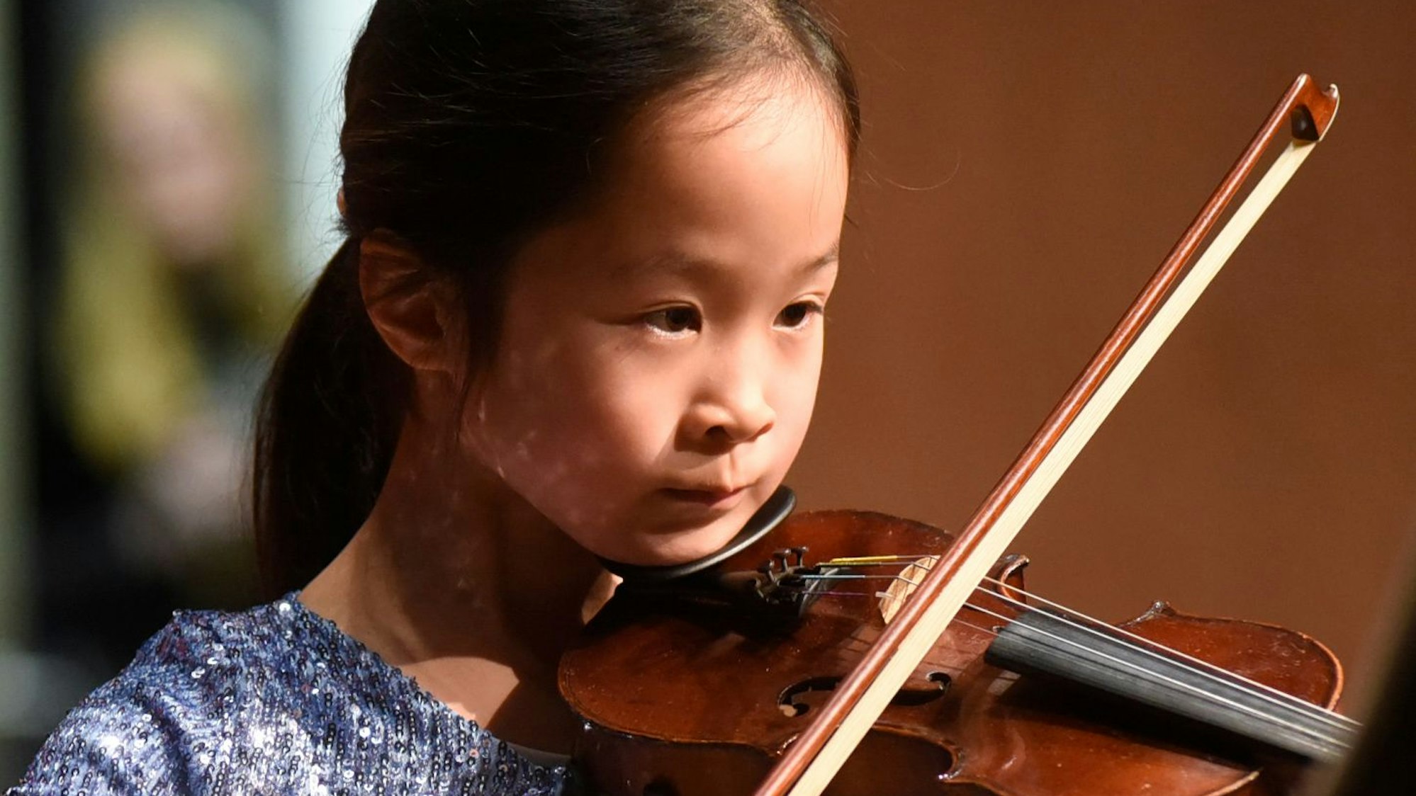 Auf dem Foto ist ein Mädchen zu sehen, das Geige spielt.