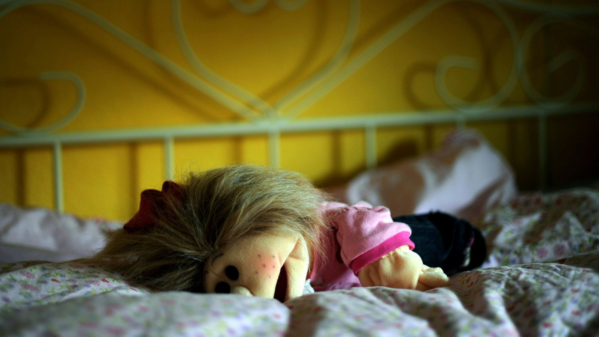 Eine Puppe liegt in Kassel in einem Kinderzimmer auf dem Bett.