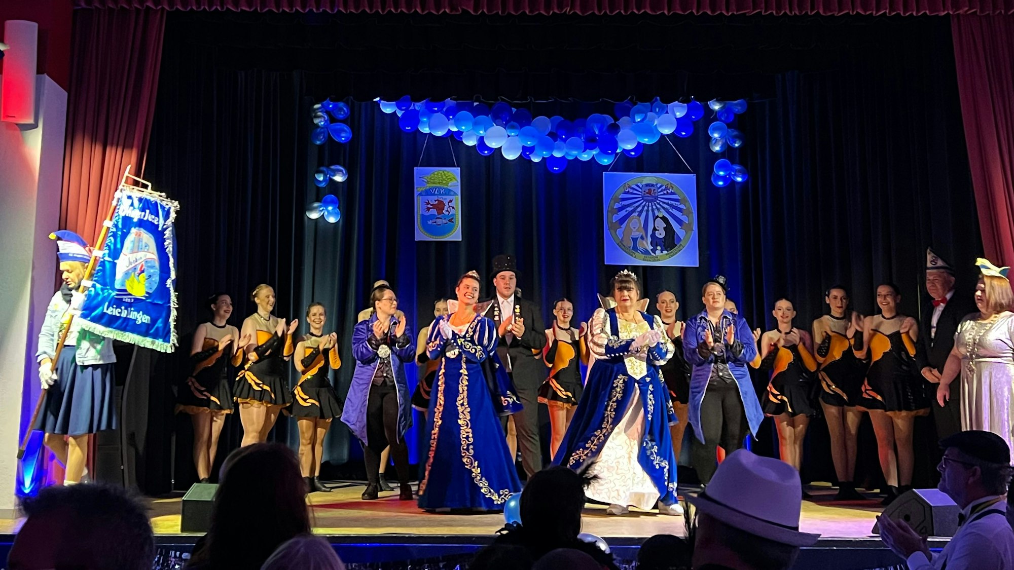 Frauen im Karnevalsornat und Tänzerinnen stehen auf einer Bühne.