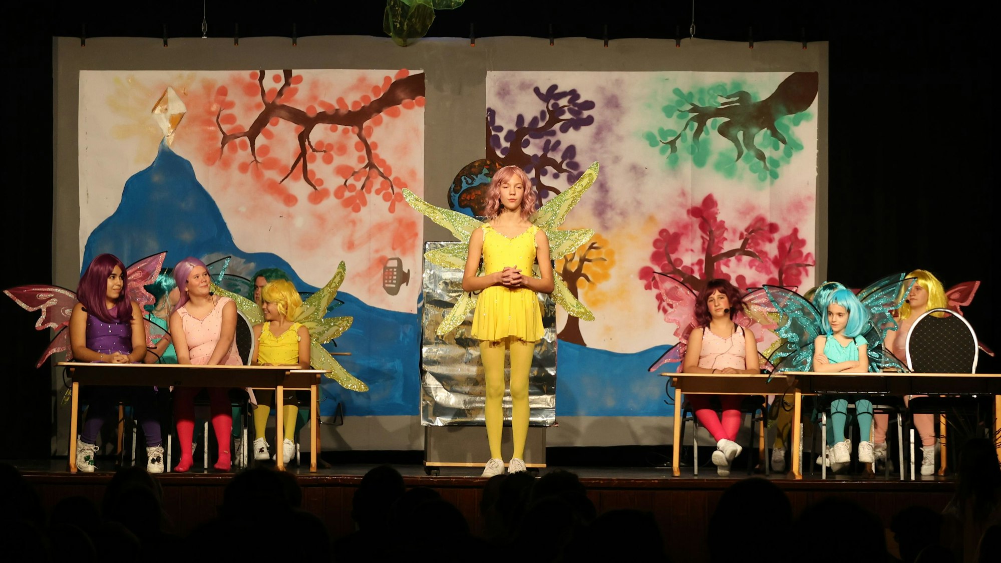 Kinder stehen und sitzen in Engelskostümen auf einer Bühne.