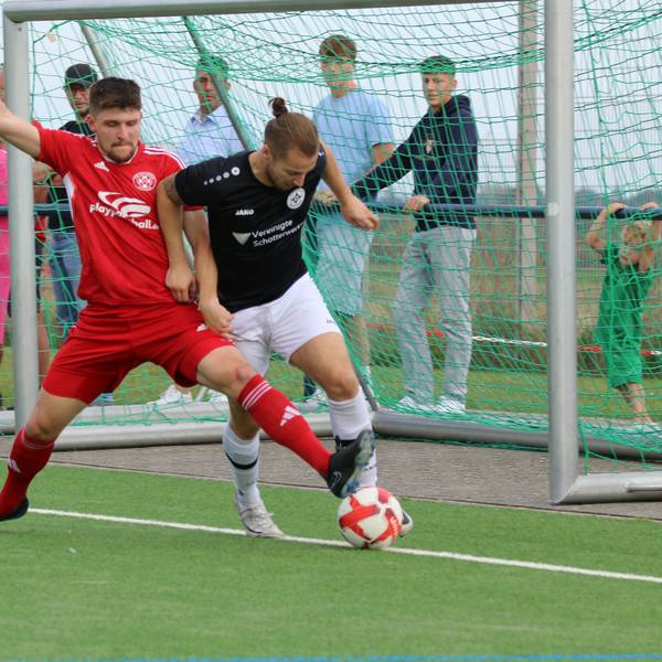 Ein Fußballer erobert mit einem langen Bein an der Außenlinie den Ball von einem Gegenspieler.
