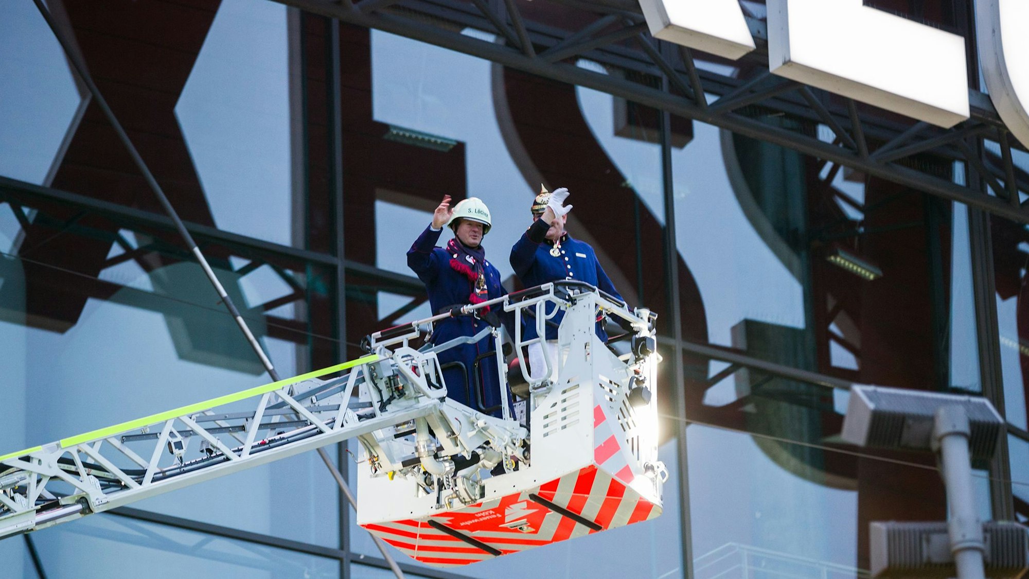 In luftiger Höhe unterwegs: Ehrenbrandmeister Stefan Löcher und Funktentöter-Präsident Guido Thiemermann im Rettungskorb der Drehleiter. vor der Lanxess-Arena.