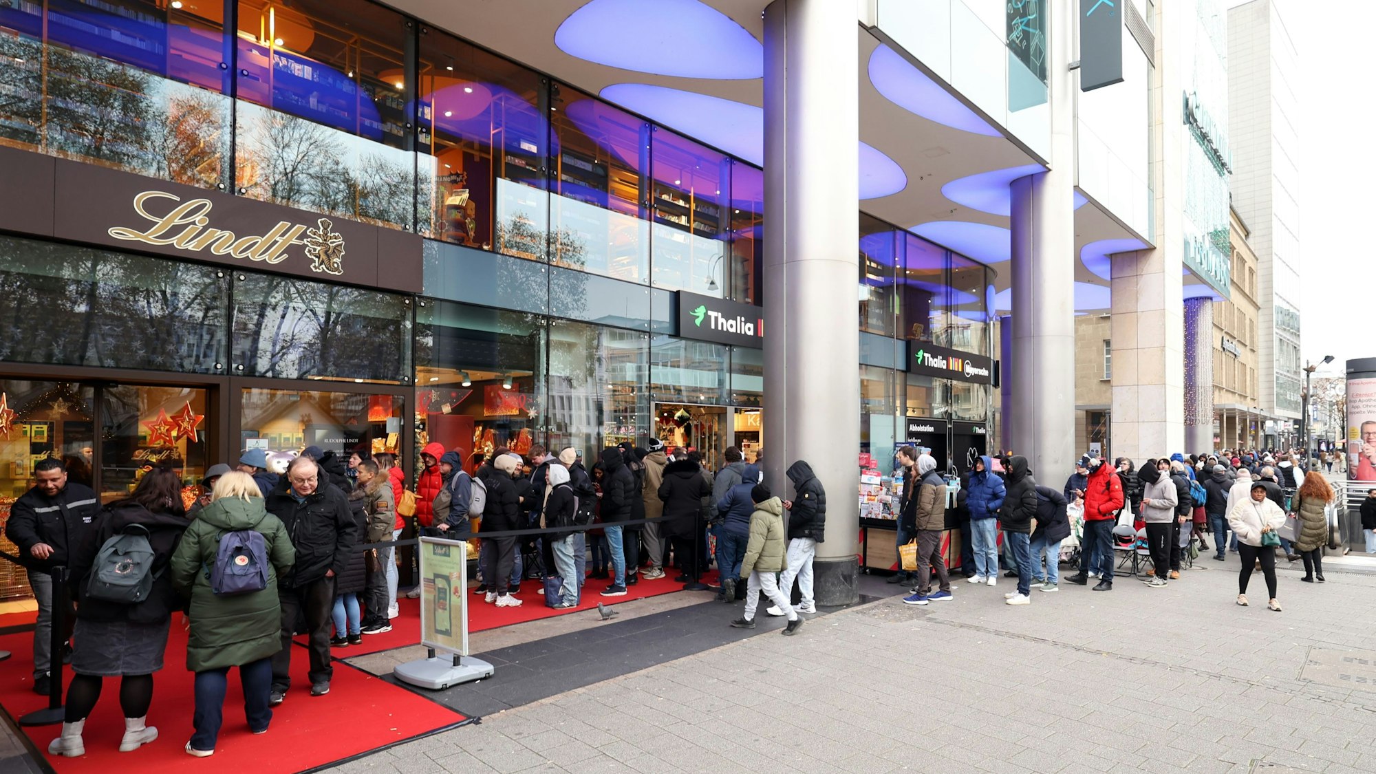 Zahlreiche Menschen stehen vor einem Geschäft Schlange.