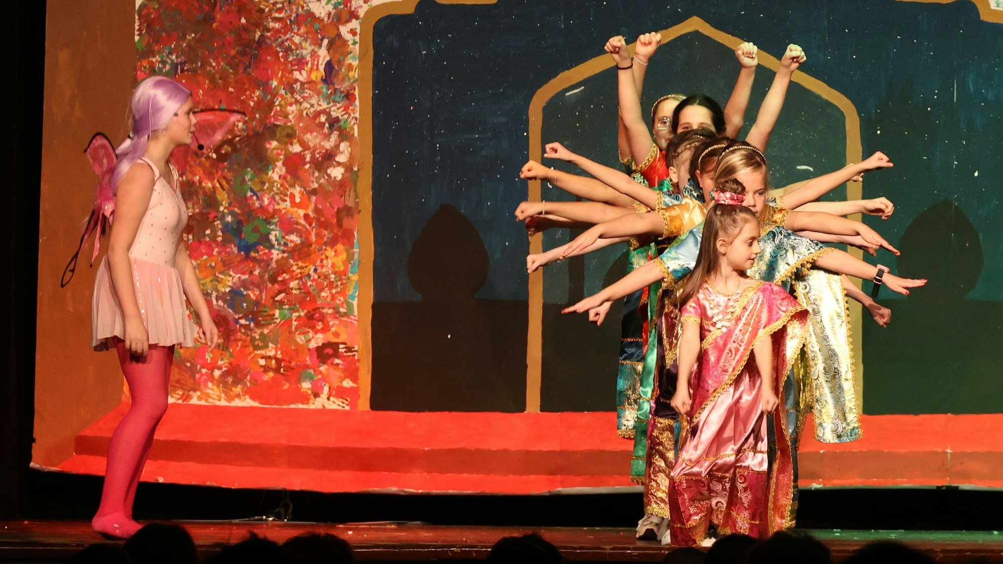 Kinder stehen auf einer Bühne und tanzen.