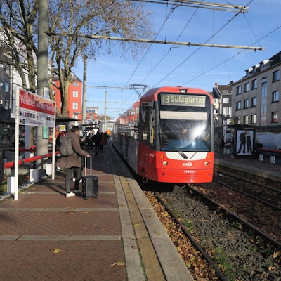 An einer Haltestelle der Straßenbahn fährt ein Zug der Linie 13 ein.