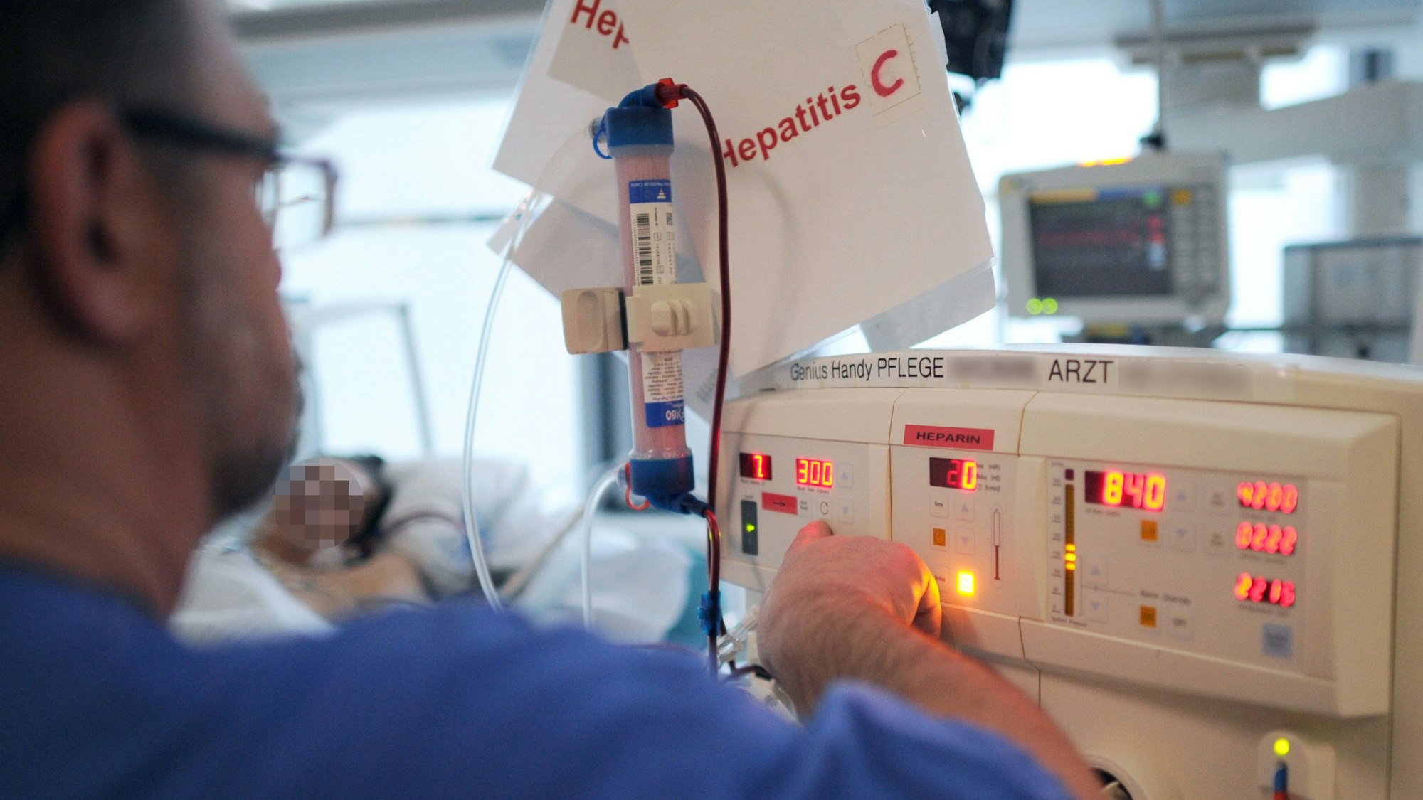 Ein Pfleger kümmert sich in einem Klinikum auf der Intensivstation um einen Patienten mit Hepatitis C.