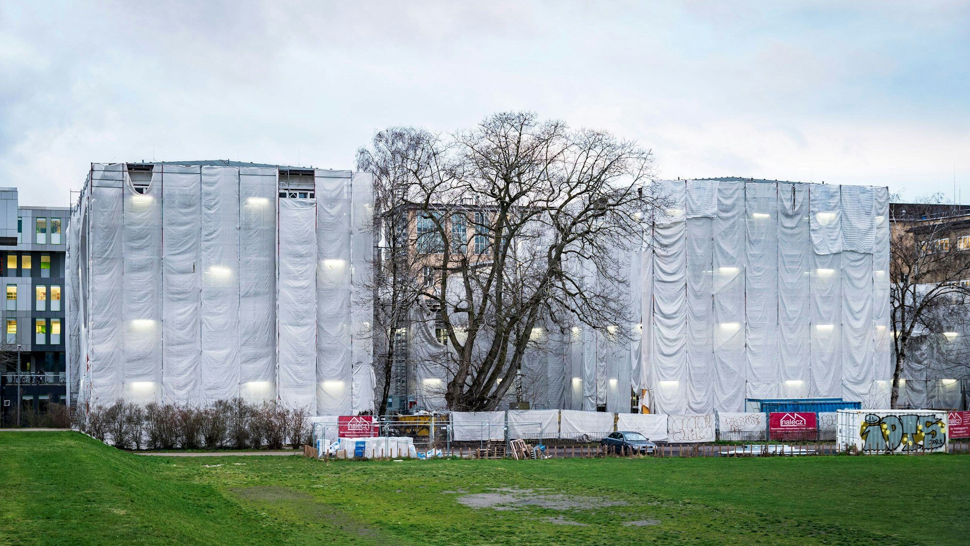 Zwei der Hauptgebäude sind wegen einer Sanierung komplett mit Gebäudeverhüllungsmaterial eingehüllt.