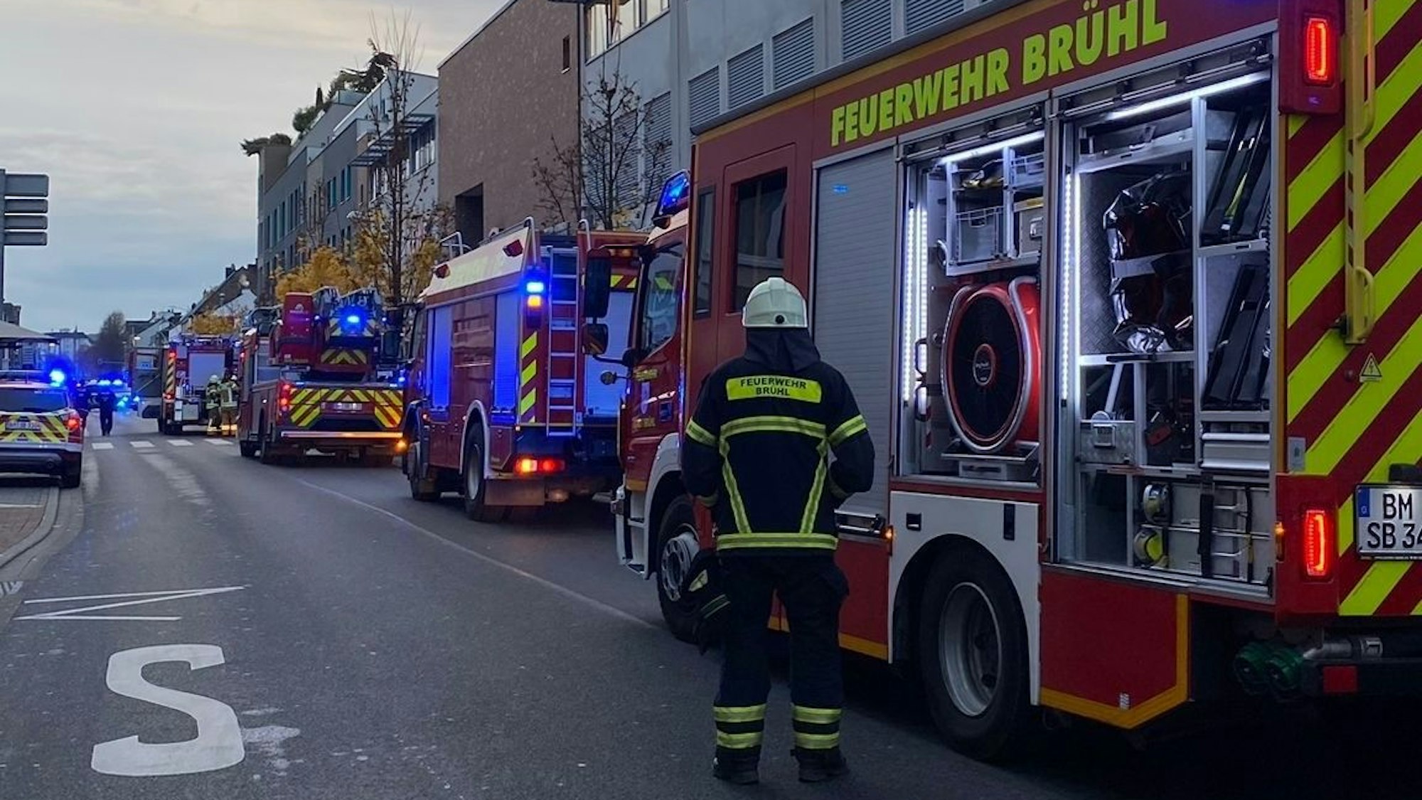 Ein Feuerwehrmann steht vor einem Feuerwehrwagen am Einsatzort.