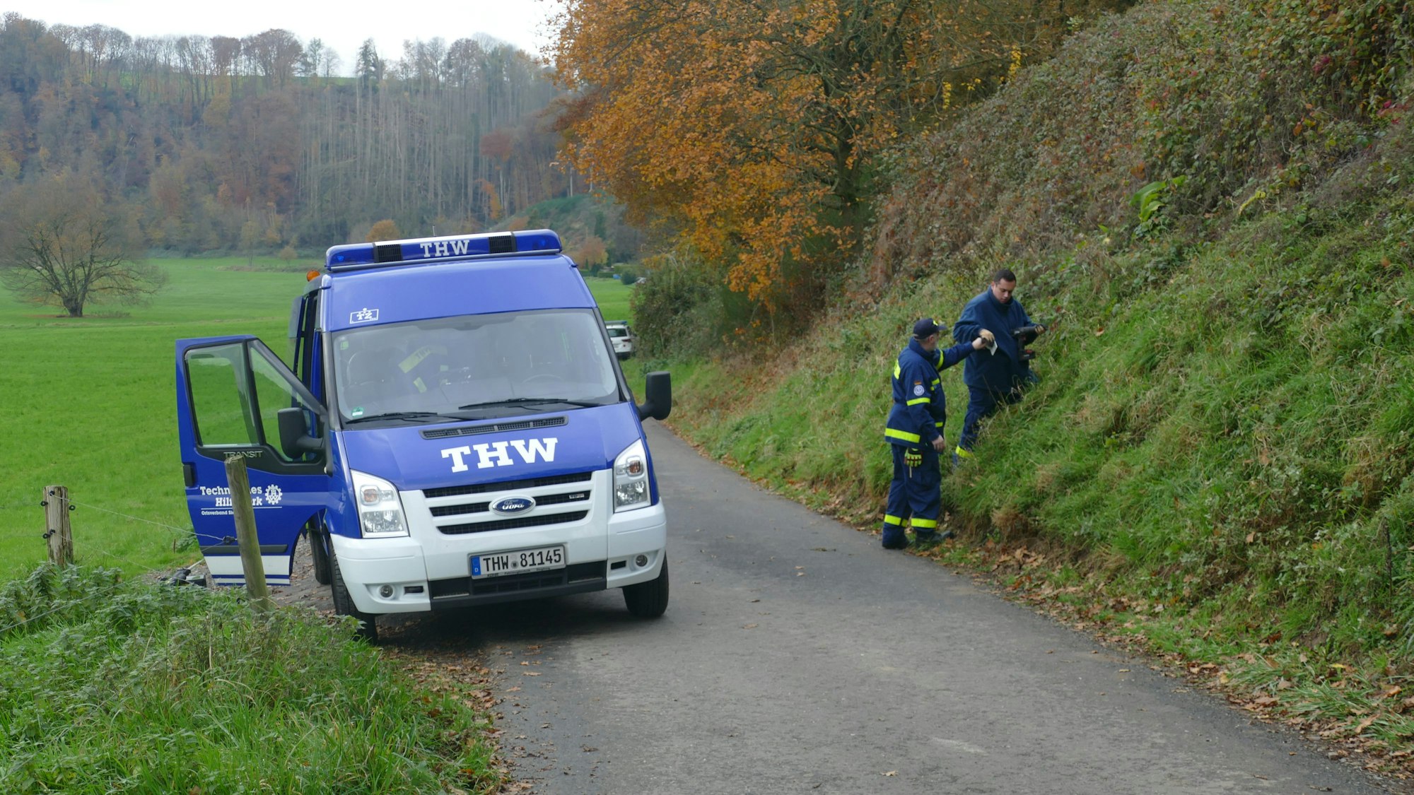 Mitarbeiter des THW untersuchen einen Hang.
