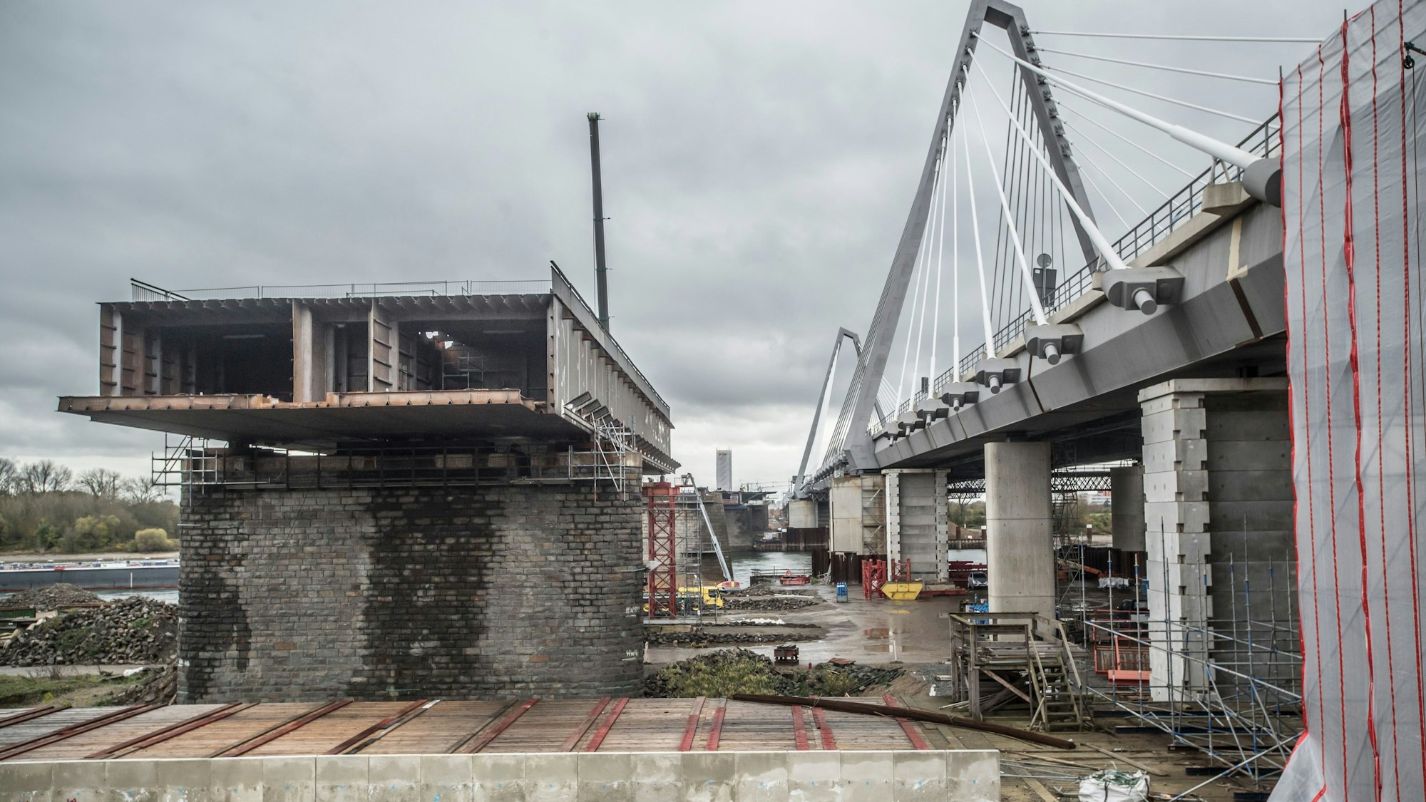 Ein Rest der alten Leverkusener Autobahnbrücke steht noch. Etwa an der Stelle wird bald mit dem Neubau des Brückenzwillings begonnen: Mit Ausschachtungsarbeiten unter einer Einhausung, weil dort giftige Abfälle liegen.