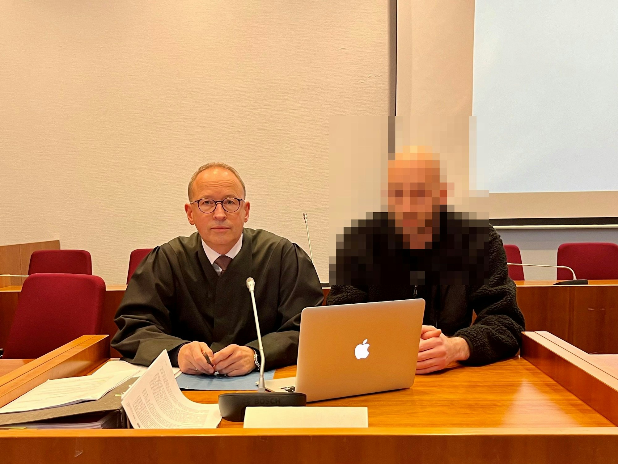 Zwei Männer sitzen nebeneinander hinter einem Tisch.