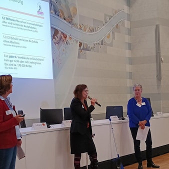 Zu sehen sind drei Frauen vor einer Beamer-Präsentation.