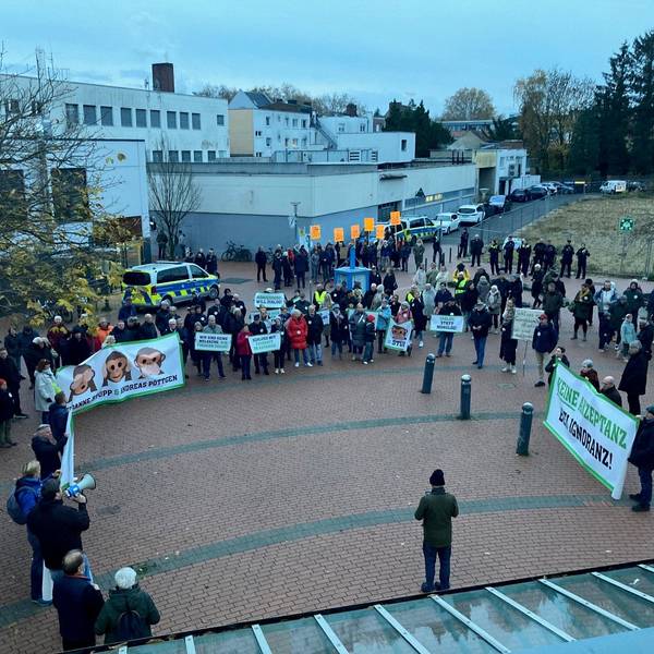 Auf dem Bild sind Menschen mit Transparenten und Schildern vor dem Stadtsaal in Frechen zu sehen.