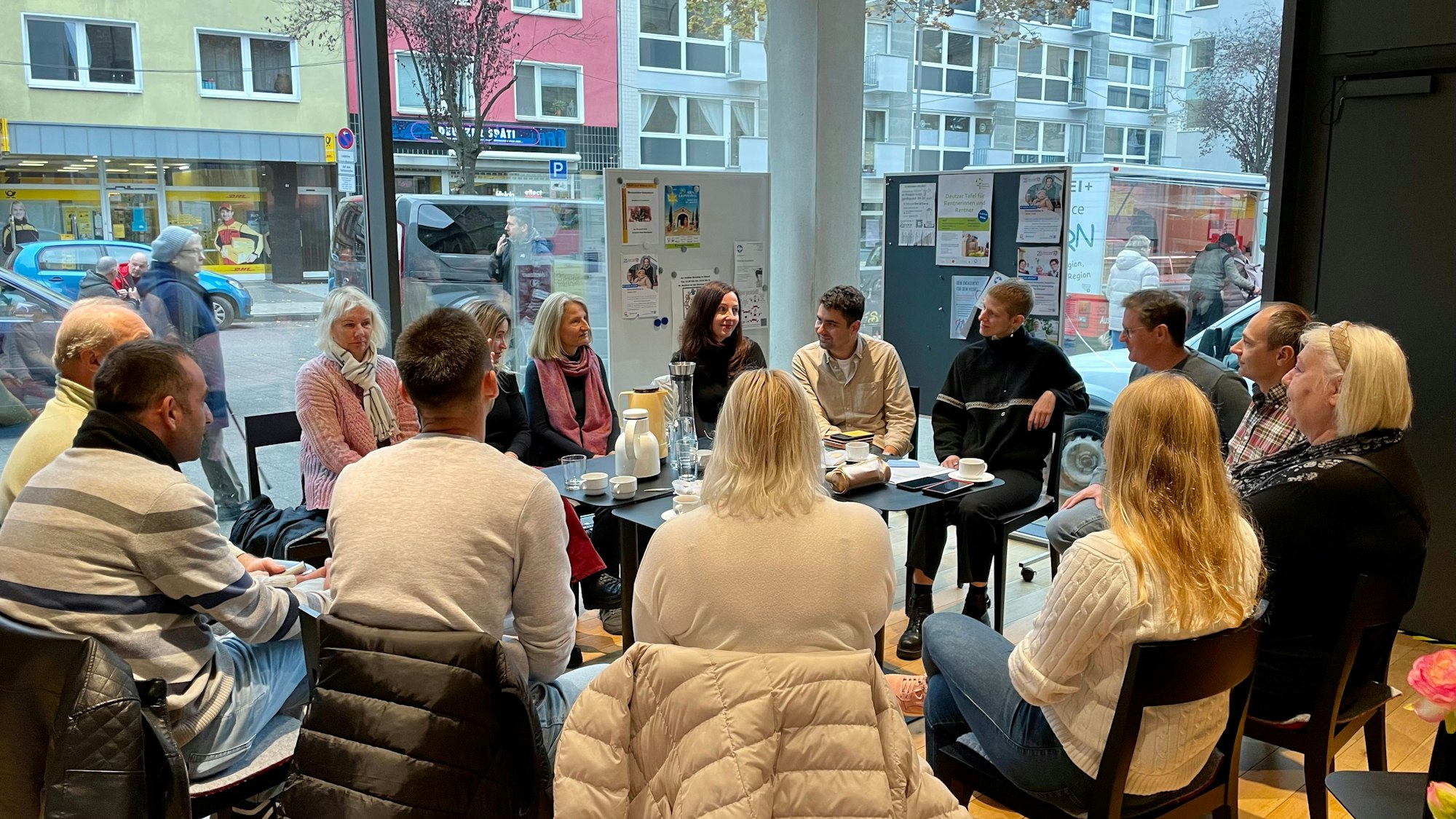 Birgit Ocken sitzt im Kreis von Menschen in einem Café um den Tisch herum.