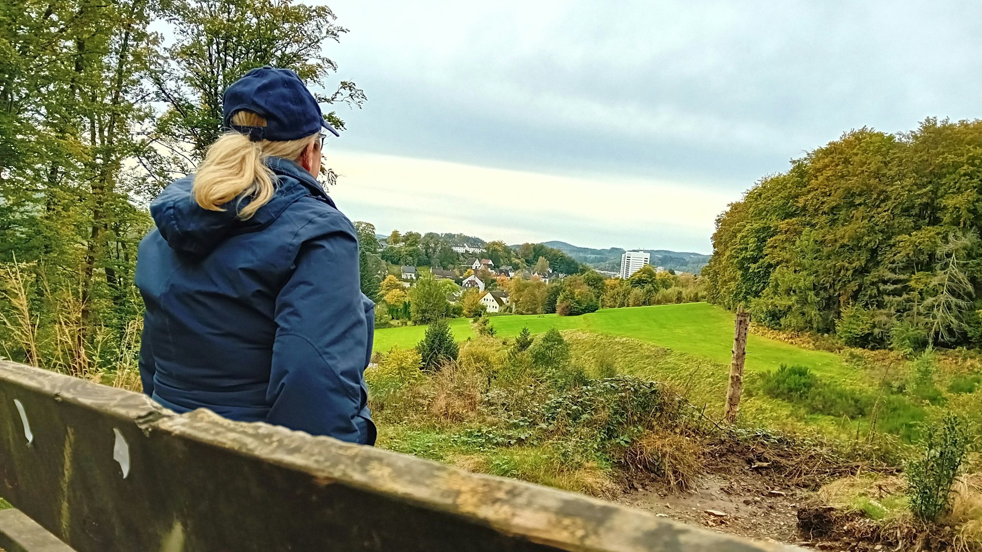 Eine Frau sitzt auf einer Bank und blickt in die Ferne.