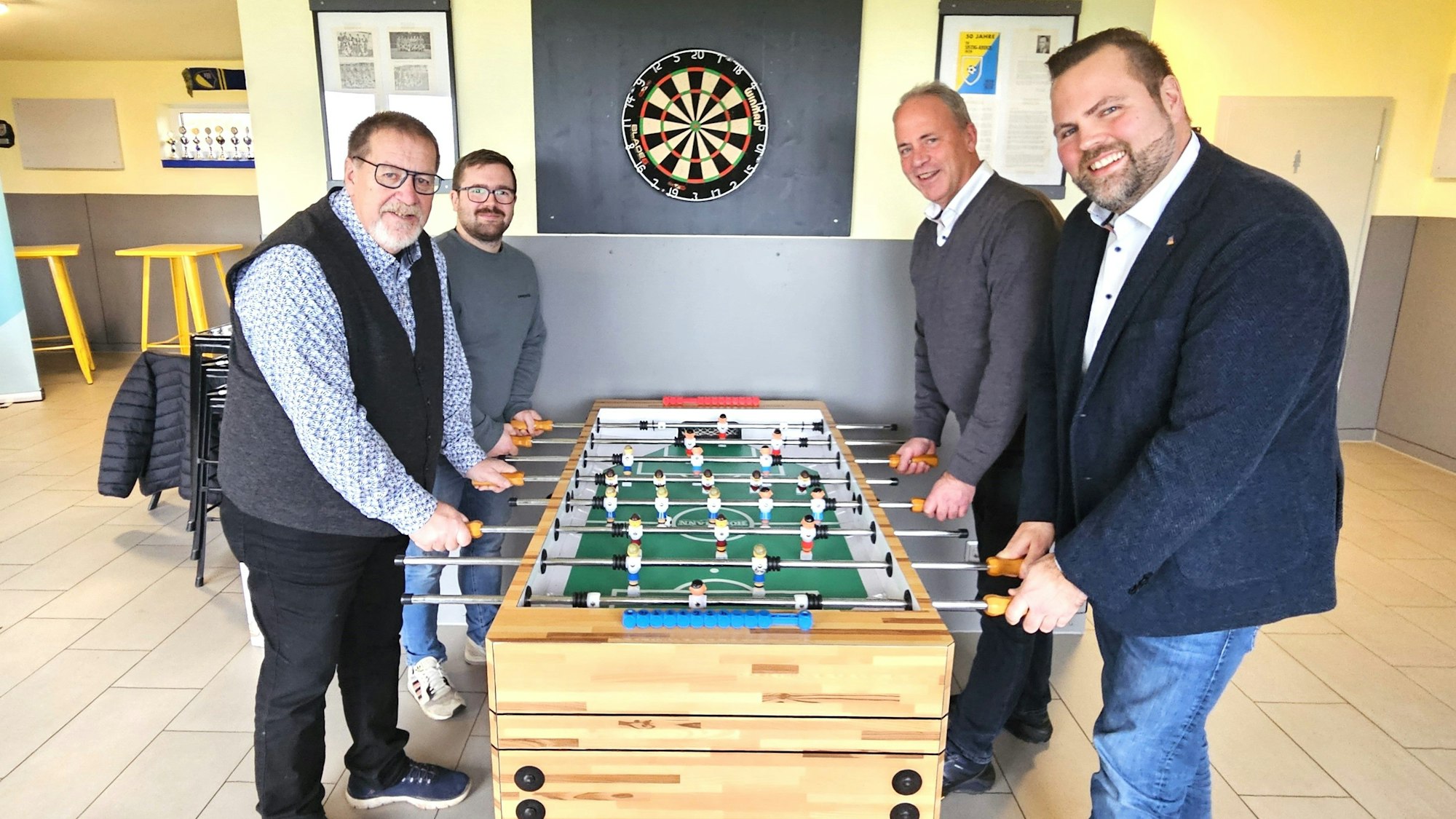 Michael Kehren, Bert Spilles, Brian Linden und Hermann-Josef Esser stehen an einem Fußballkicker.