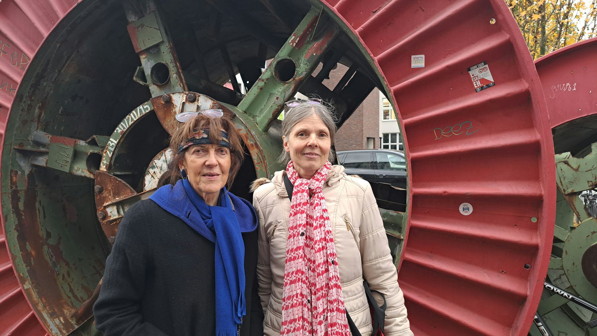 Zwei Frauen stehen vor einem ausrangierten Industrie-Denkmal.