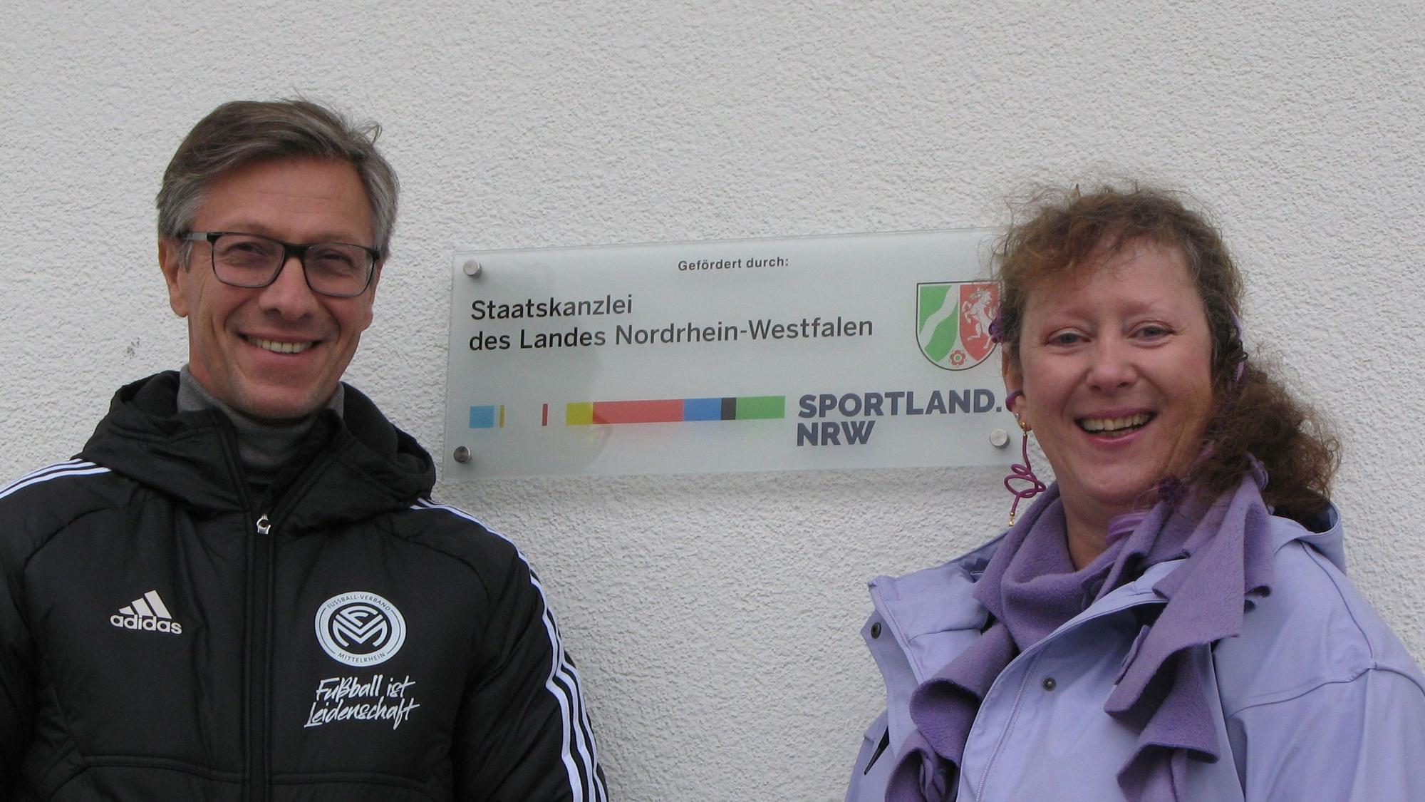 Ein Mann und eine Frau an einem Schild der Staatskanzler des Landes Nordrhein-Westfalen.