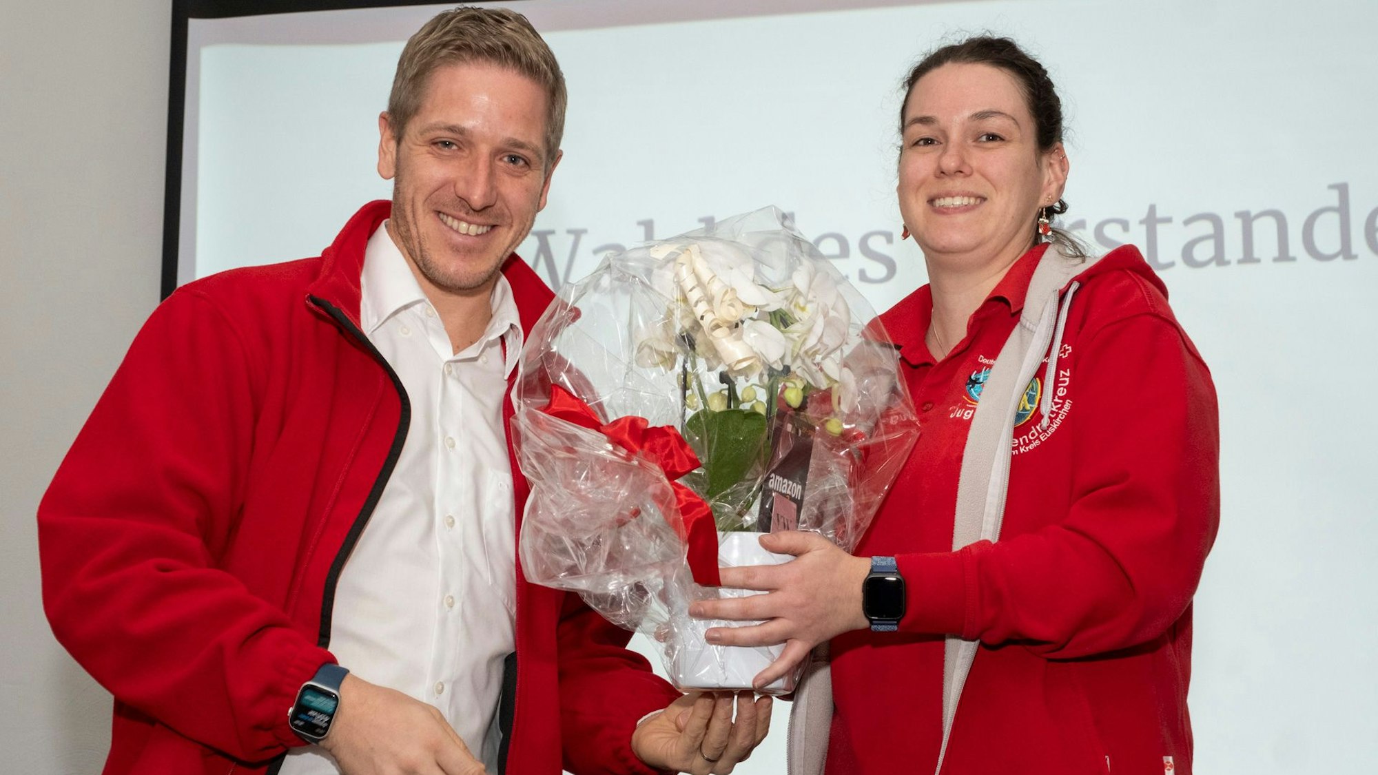 Landrat Ramers überreicht Schwade einen Blumenstrauß, der in durchsichtiger Folie verpackt worden ist.