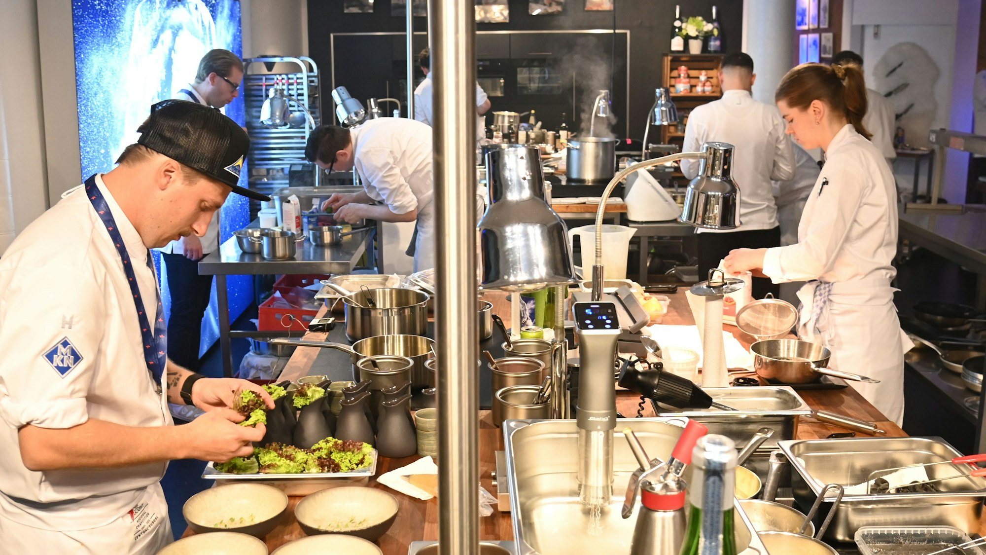 Blick in eine Küche, in der mehrere Köche ihre Gerichte zubereiten.