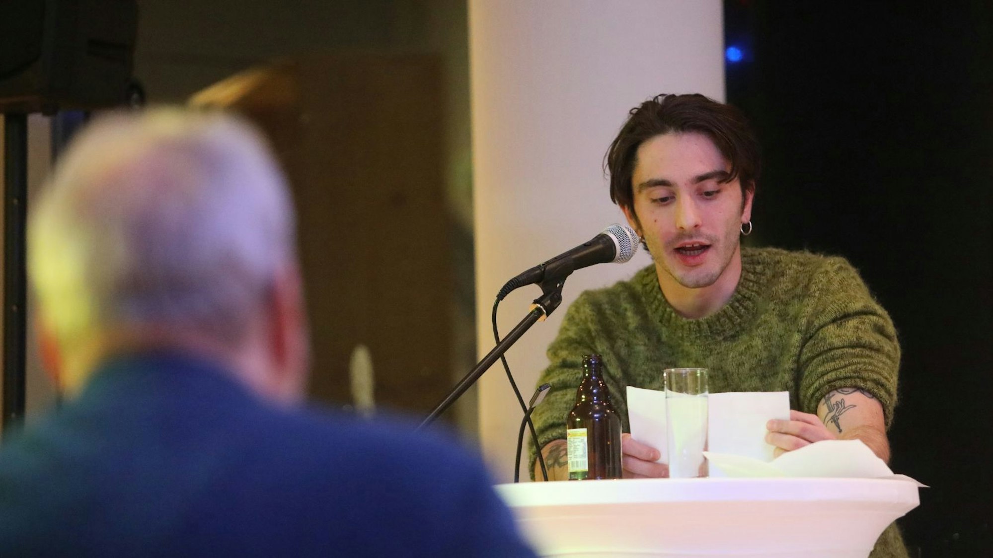 Ein junger Mann im grünen Pullover beim Lesen eines Textes.