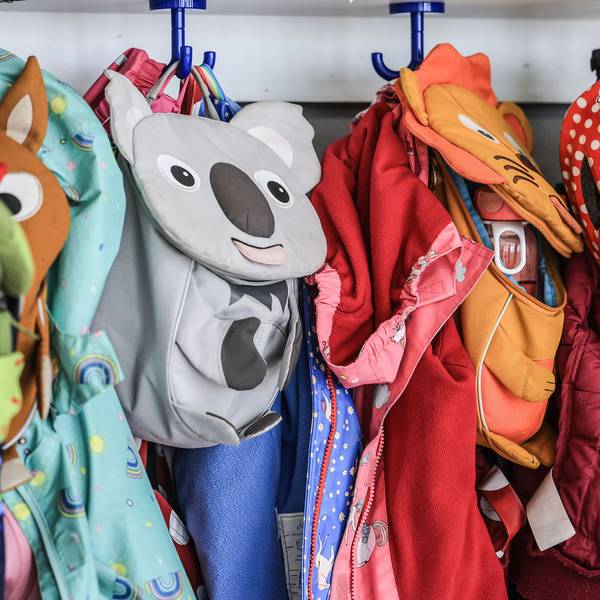 Kleidung und Taschen von Kindern hängen im Flur einer Kindertagesstätte.