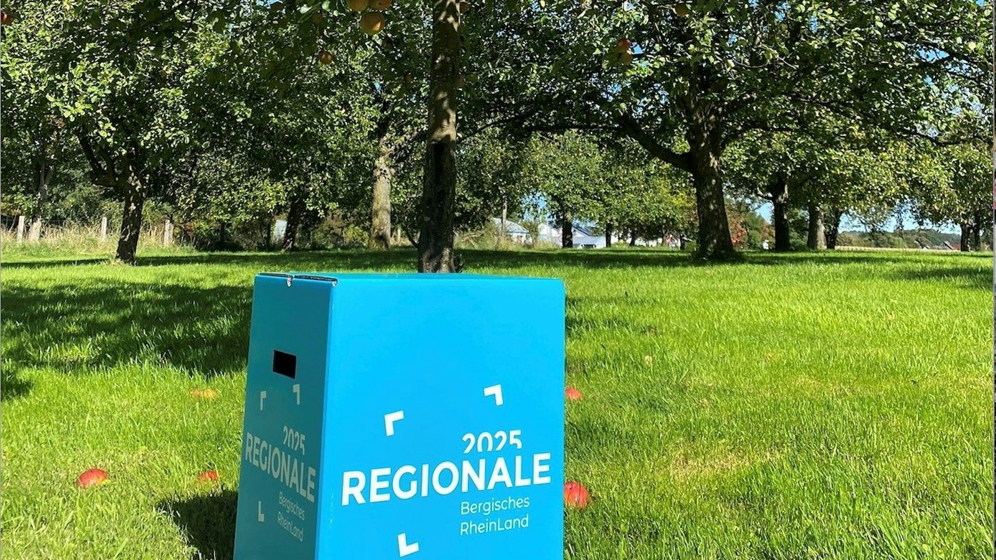 Ein Schild steht vor Obstbäumen.