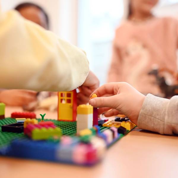 Kinder spielen in einer Kita mit Legosteinen.